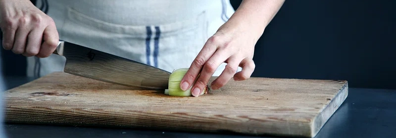 A woman cutting an onion on a cutting board