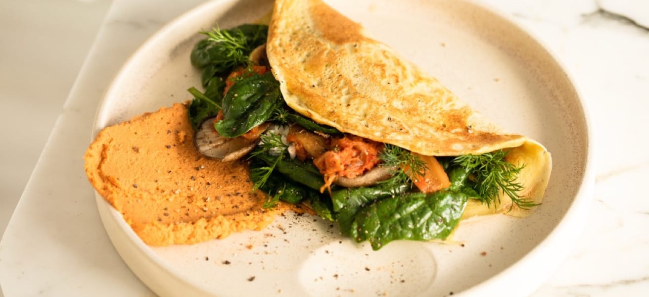 Image of a cooked Omelette filled with vegetables, with toast on the side.